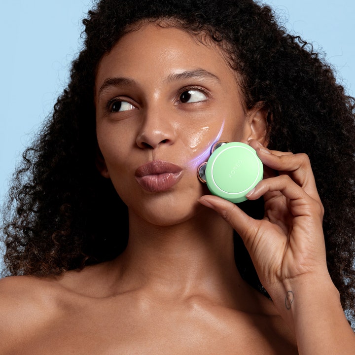 FOREO BEAR 2 go Pistachio 1 kpl kasvojen kiinteyttäjä jota nainen käyttää poskellaan luoden hehkua.