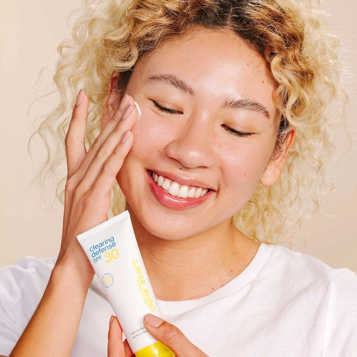 Dermalogica Clear Start Clearing Defense SPF30 suojaava päivävoide tuubissa jota nainen levittää kasvoilleen