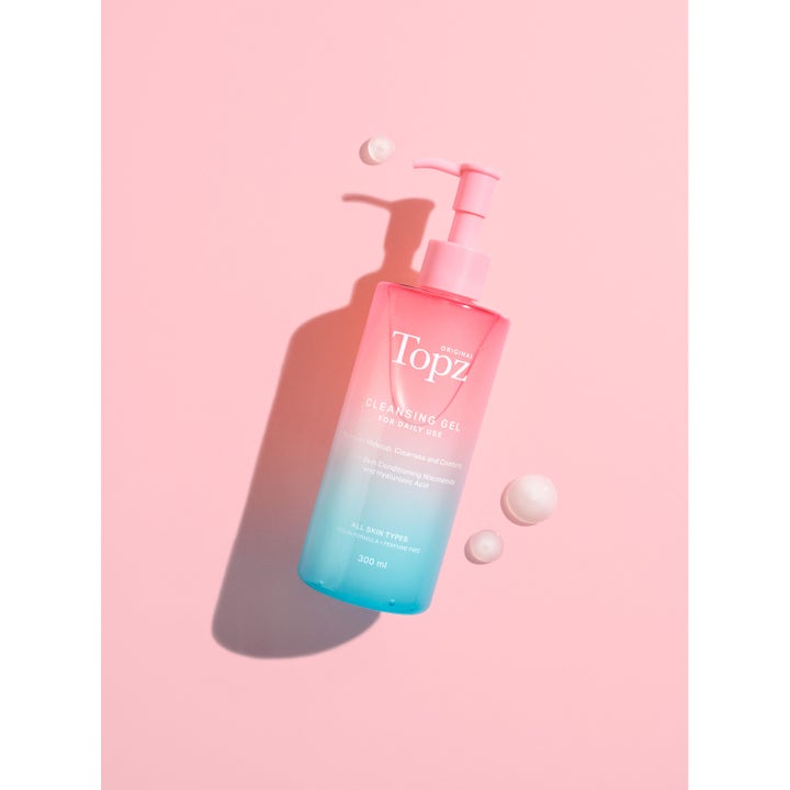 Topz Daily Cleansing Gel 300 ml puhdistusgeeli niasiiniamidilla liukuvärjätyssä pullossa vaaleanpunaisella taustalla.