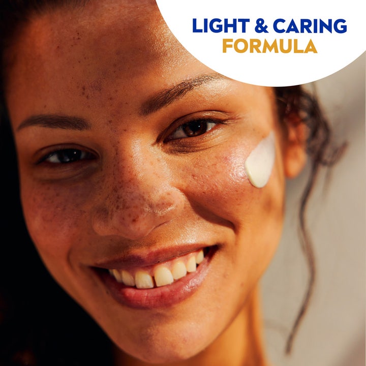NIVEA UV Face Sensitive SPF50 50 ml rauhoittava aurinkovoide, jota hymyilevä nainen levittää kasvoilleen.