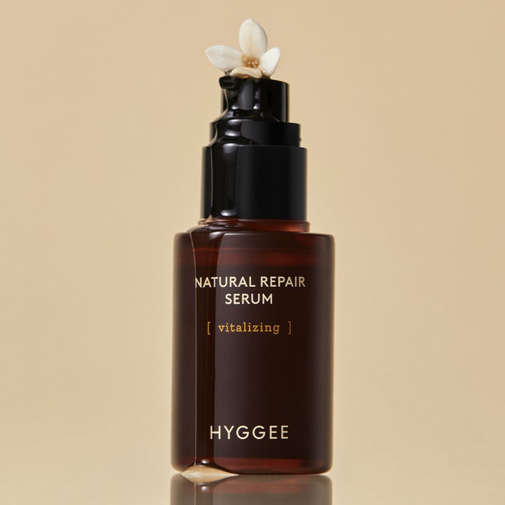 Hyggee Natural Repair Serum 30 ml elvyttävä seerumi ruskeassa lasipullossa, jossa on valkoinen kukka ja valuvaa seerumia.