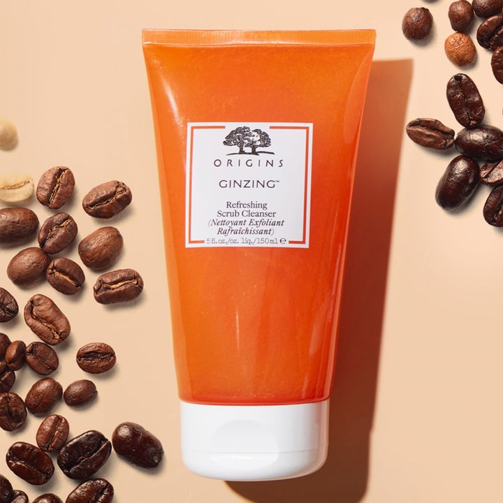 Origins GinZing Refreshing Scrub Cleanser 150 ml kirkastava kuorintavoide oranssissa tuubissa kahvipapujen keskellä