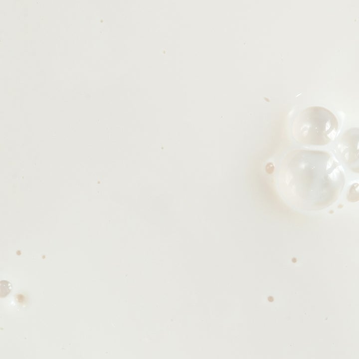 KORA Organics Silky Sun Drops 30 ml aurinkosuojaseerumi, jossa on silkkisen pehmeä valkoinen koostumus ilmakuplilla.