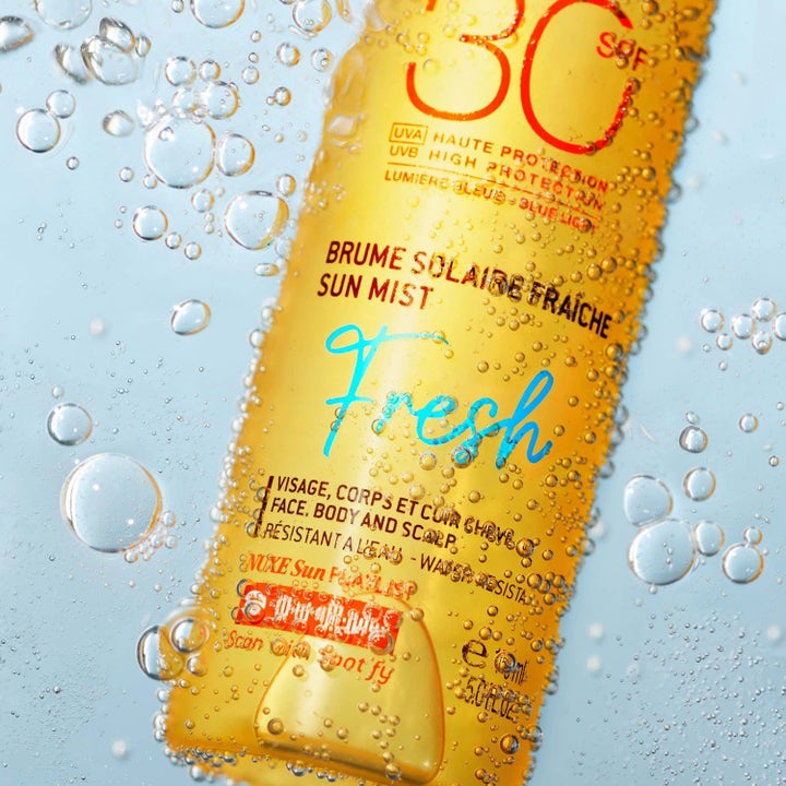 Nuxe Sun Mist Fresh SPF 30 150 ml aurinkosuihke vartalolle oranssissa pullossa vesikuplien ympäröimänä.