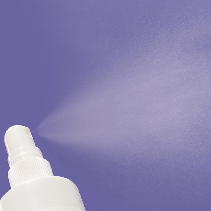 Mario Badescu Repairing Facial Spray 118 ml face mist suihkuttaa hienojakoista sumua lilaa taustaa vasten.