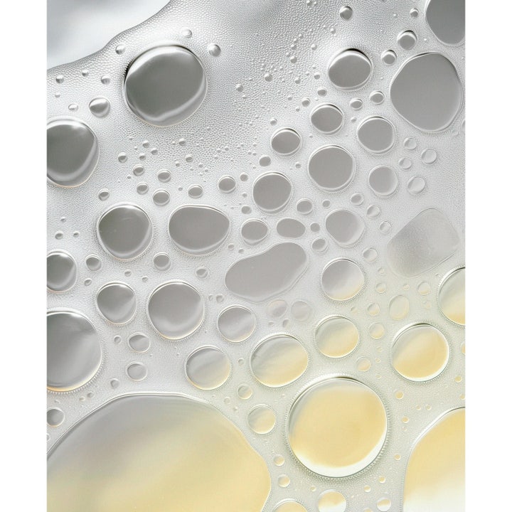 MANTLE The Nourishing Body Wash 250 ml kosteuttava suihkugeeli, jossa näkyy öljyisiä kuplia kirkkaassa nesteessä.
