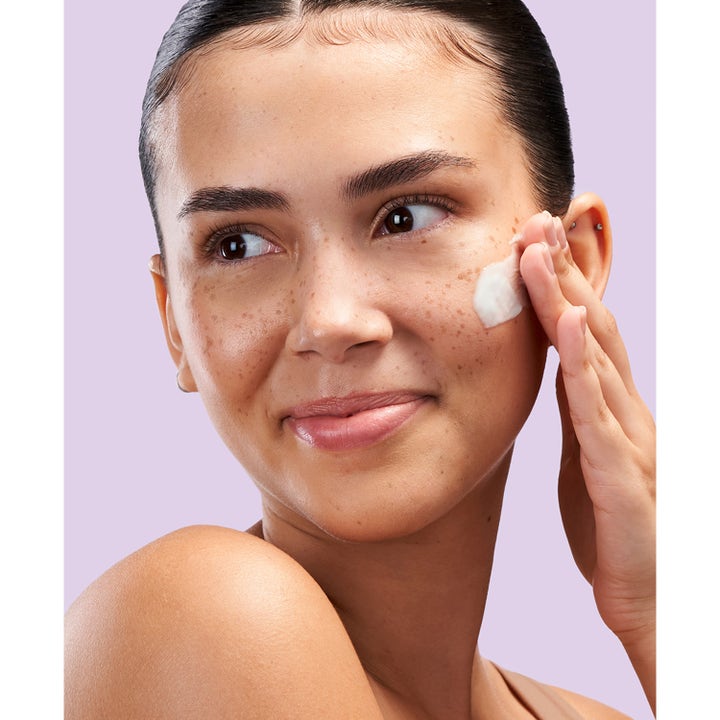 Exuviance Pro-Plump Hydrating Cream 45 g kosteuttava yövoide jota nainen levittää poskelleen.