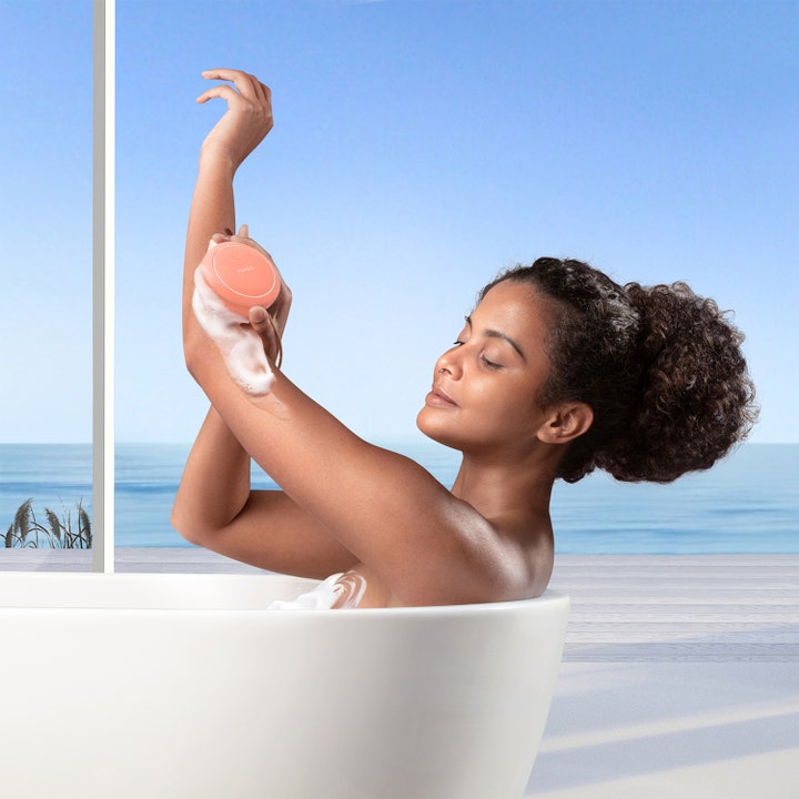 FOREO LUNA 4 body Peach Perfect 1 kpl syväpuhdistava vartalonpuhdistuslaite nainen käyttää laitetta kylvyssä vaahdon kera.