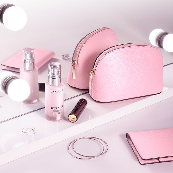 Lancôme Hydra Zen Liquid Moisturizer 50 ml kosteuttava kasvovoide vaaleanpunaisessa pumppupullossa meikkipussien kera.