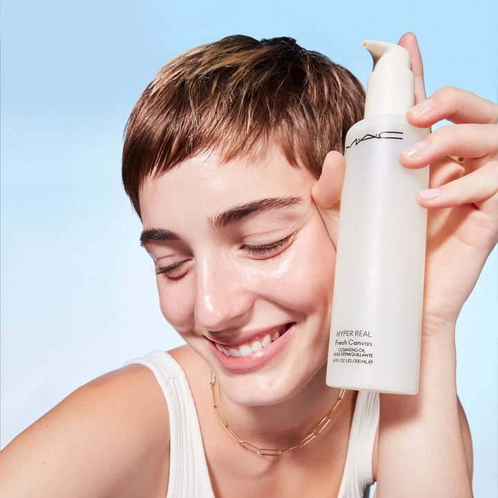 MAC Cosmetics Hyper Real Fresh Canvas Cleansing Oil 200 ml puhdistusöljy valkoisessa pumppupullossa henkilön pitelemänä