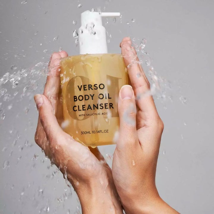Verso N°10 Body Oil Cleanser 300 ml kuoriva suihkuöljy kirkkaassa pumppupullossa vesiroiskeiden ympäröimänä.