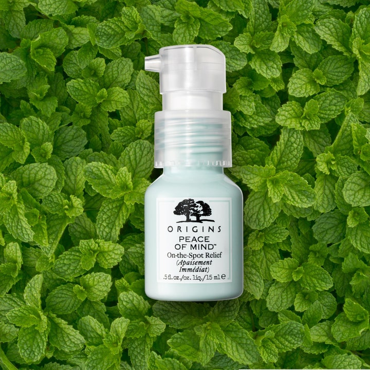 Origins Peace Of Mind On The Spot Relief 15 ml lievittävä täsmätuote vaaleansinisessä pullossa mintunlehtien päällä