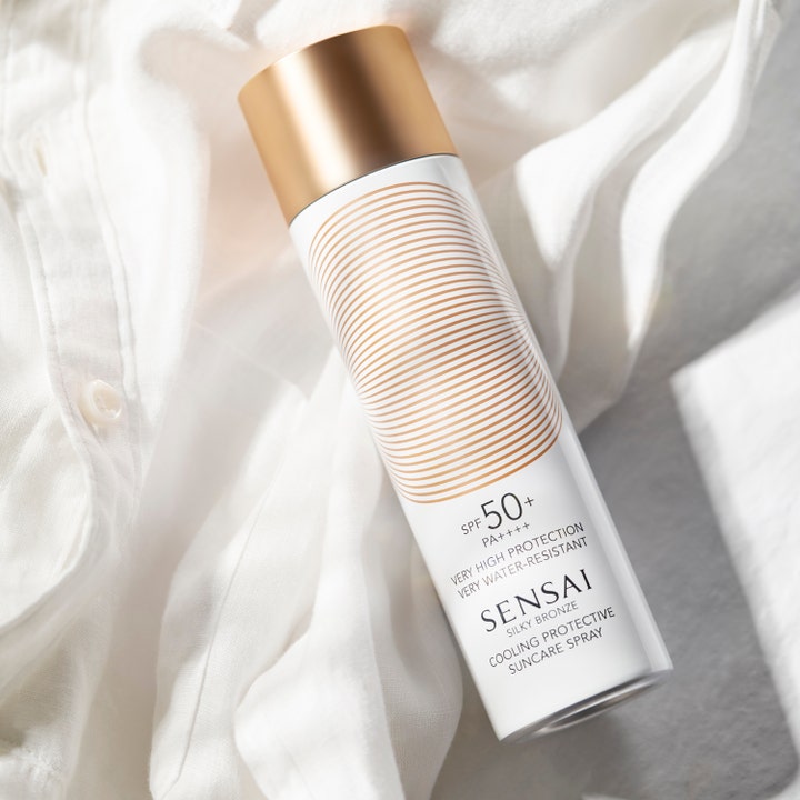 Sensai Silky Bronze Cooling Protective Suncare Spray 150 ml SPF50 aurinkovoide valkoisessa kultakorkkisessa pullossa.