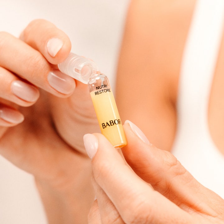Babor Nutri Restore Ampoule 14 ml ravitseva seerumi lasiampullissa josta valuu kultaista nestettä kämmenelle.