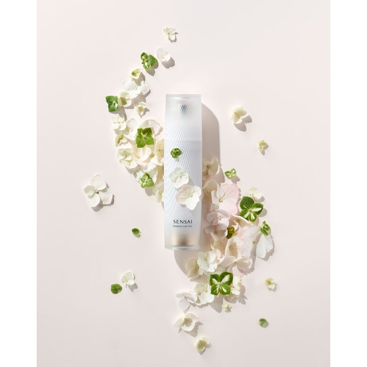 Sensai Essence Day Veil 40 ml suojaava päivävoide valkoisessa pullossa kukkien ja terälehtien ympäröimänä.