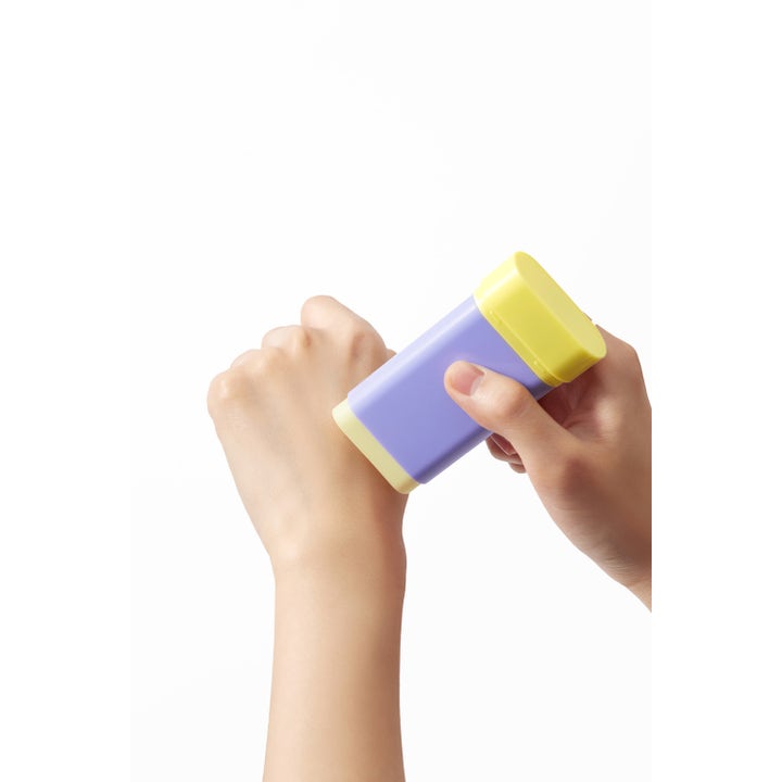 By Wishtrend Pore Smoothing Bakuchiol Sun Stick 18 g ihohuokosia tasoittava liila aurinkosuojapuikko levitettynä kädelle