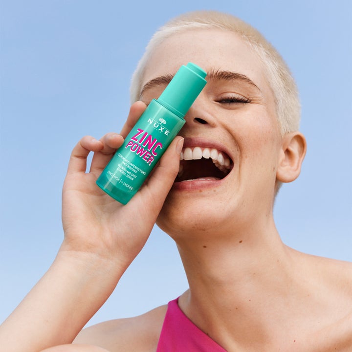 Nuxe Zinc Power 30 ml epäpuhtauksia vähentävä seerumi vaaleatukkaisen mallin kädessä.