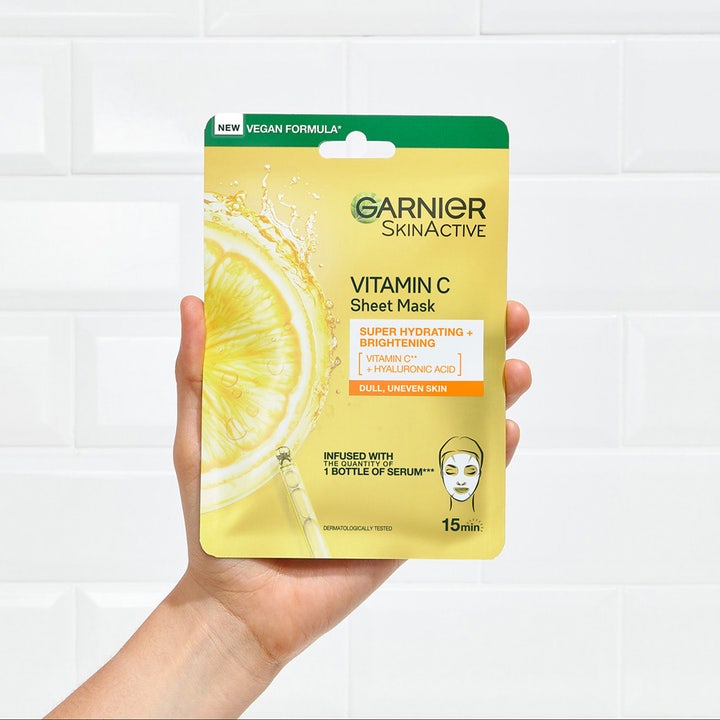 Garnier SkinActive Vitamin C Sheet Mask 28 g kirkastava kangasmaski keltaisessa pakkauksessa kädessä pidettynä