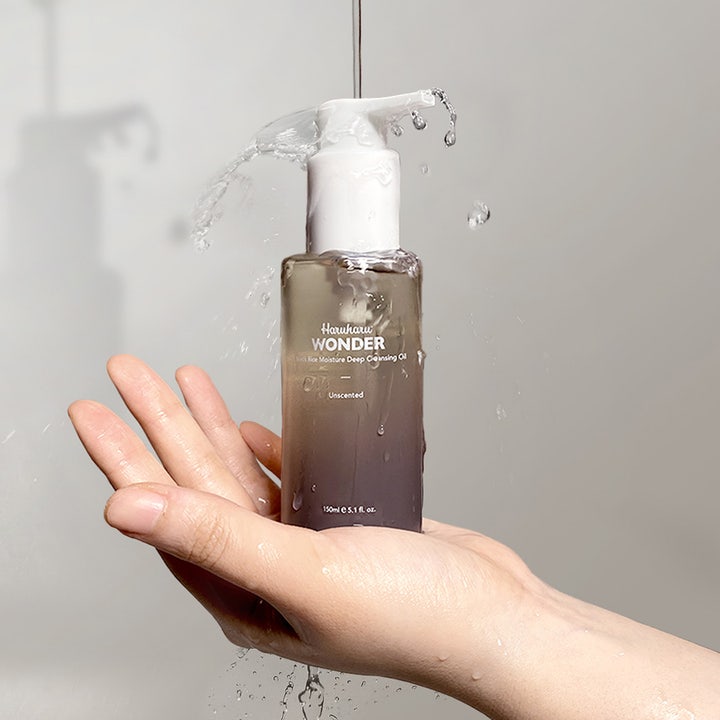 Haruharu Wonder Black Rice Moisture Deep Cleansing Oil 150 ml puhdistusöljy kämmenellä veden roiskuessa.