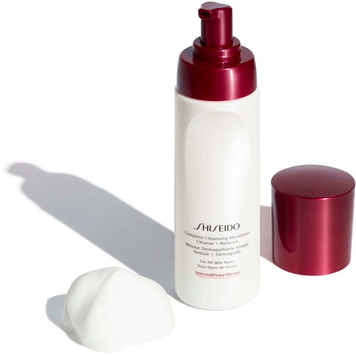 Shiseido Defend Preparation Cleansing Microfoam 180 ml puhdistusvaahto valkoisessa pullossa ja ilmavaa vaahtoa.