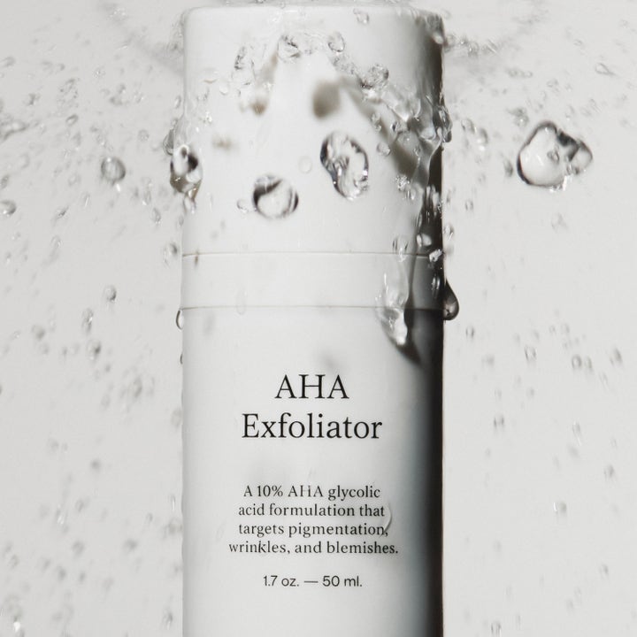 Jorgobé AHA Exfoliator 50 ml kirkastava seerumi valkoisessa pullossa raikkaiden vesiroiskeiden ympäröimänä.