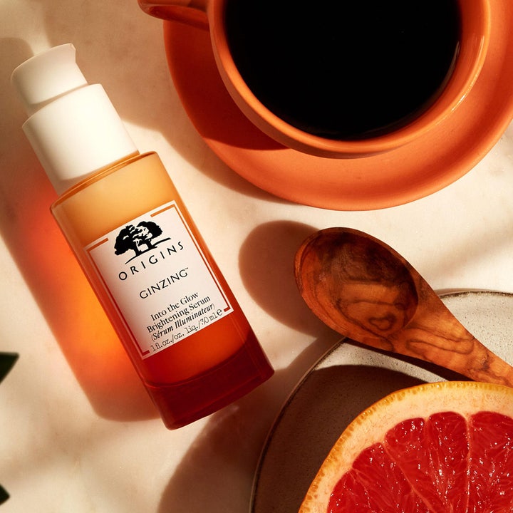 Origins GinZing Into the Glow Brightening Serum 30 ml kirkastava seerumi kahvikupin ja greipin rinnalla.