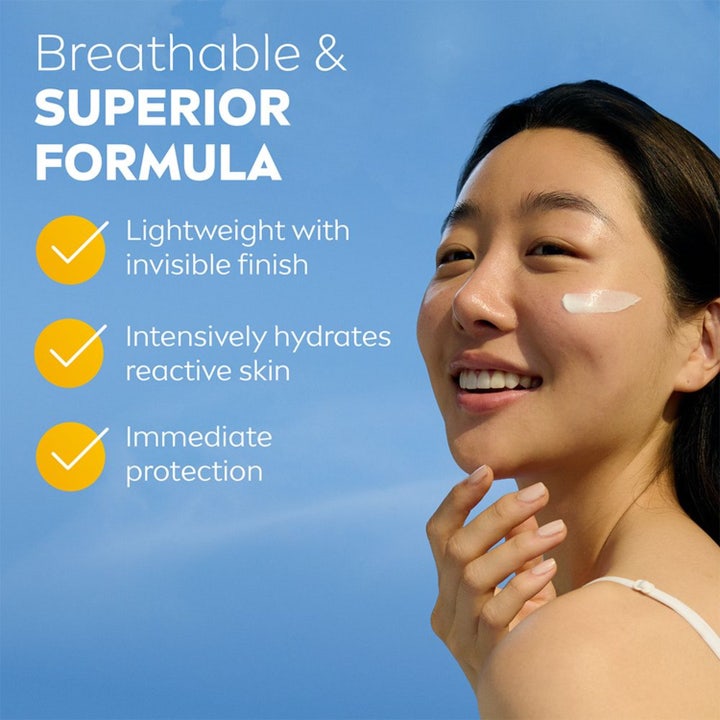 NIVEA UV Face Sensitive Cream 40 ml aurinkovoide. Hymyilevä nainen ja valkoista voidetta poskella sinistä taivasta vasten.