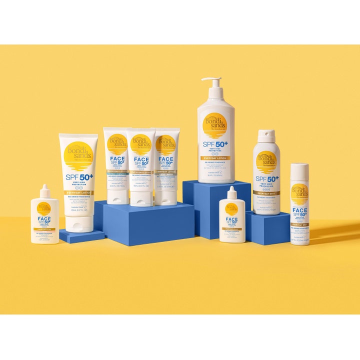 Bondi Sands SPF50+ Everyday Aerosol Mist Spray 160 g aurinkosuihke osana tuoteperhettä sinisillä korokkeilla.