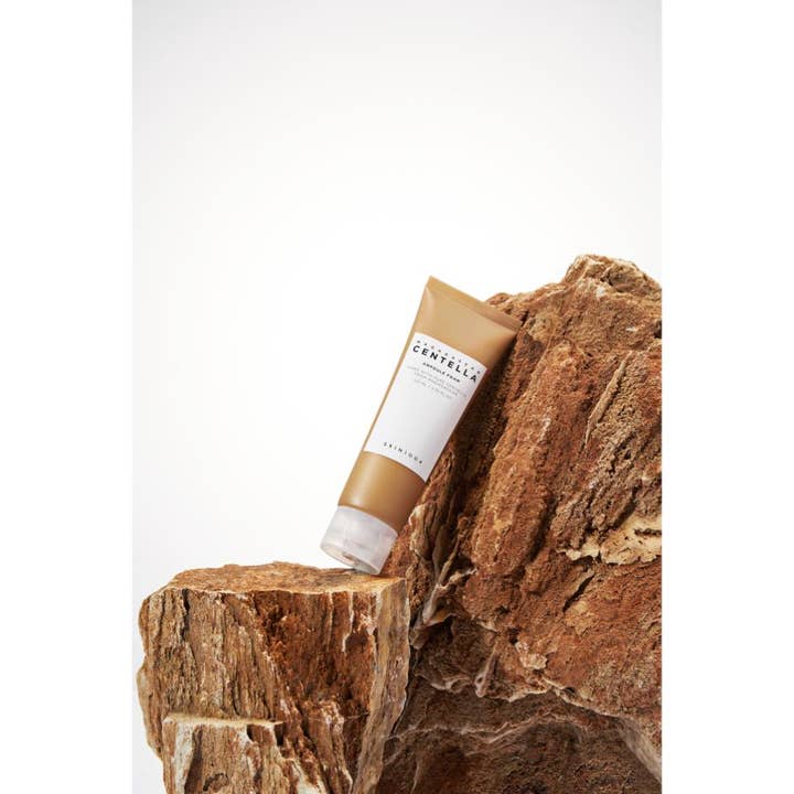 SKIN1004 Madagascar Centella Ampoule Foam 125 ml rauhoittava puhdistusvaahto ruskeassa tuubissa vasten rosoista kiveä