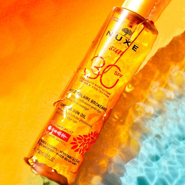 Nuxe Sun Tanning Oil 150 ml SPF30 aurinkosuojaöljy kasvoille ja vartalolle kimaltelee oranssin veden syleilyssä.