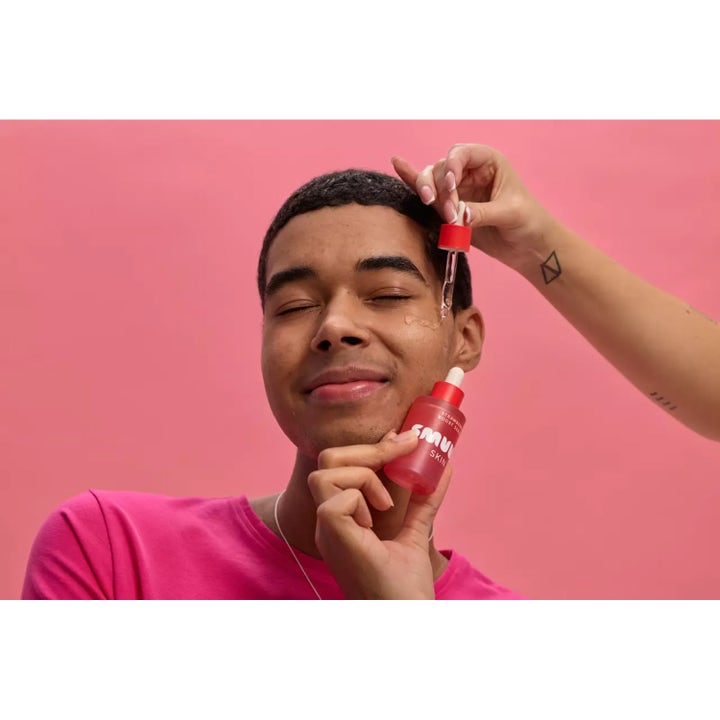 Smuuti Skin Strawberry Boost Serum 30 ml kirkastava kasvoseerumi, jota levitetään pipetillä miehen kasvoille.
