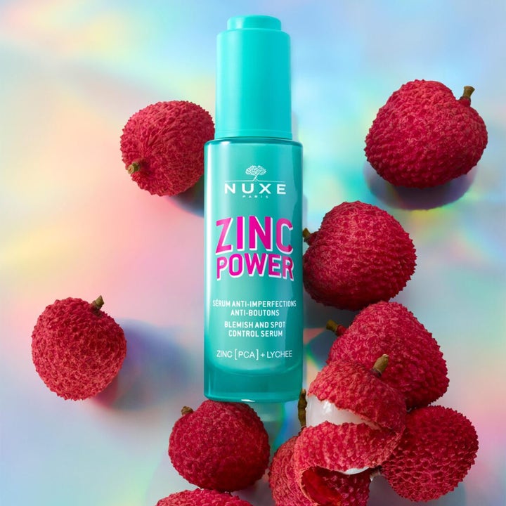 Nuxe Zinc Power 30 ml kasvoseerumi epäpuhtauksia vastaan turkoosissa pullossa litsien ympäröimänä.