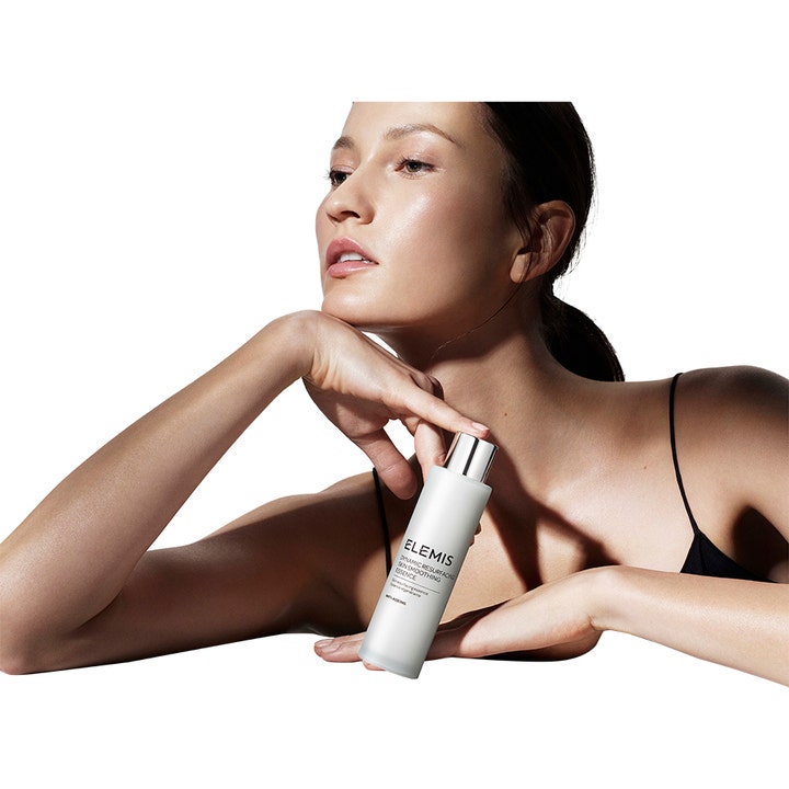 Elemis Dynamic Resurfacing Skin Smoothing Essence 100 ml silottava hoitoneste ja nainen pitelee valkoista pulloa