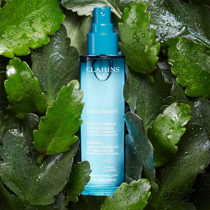 Clarins Hydra-Essentiel 75 ml kosteuttava kasvosuihke sinisessä pullossa vihreiden lehtien keskellä.