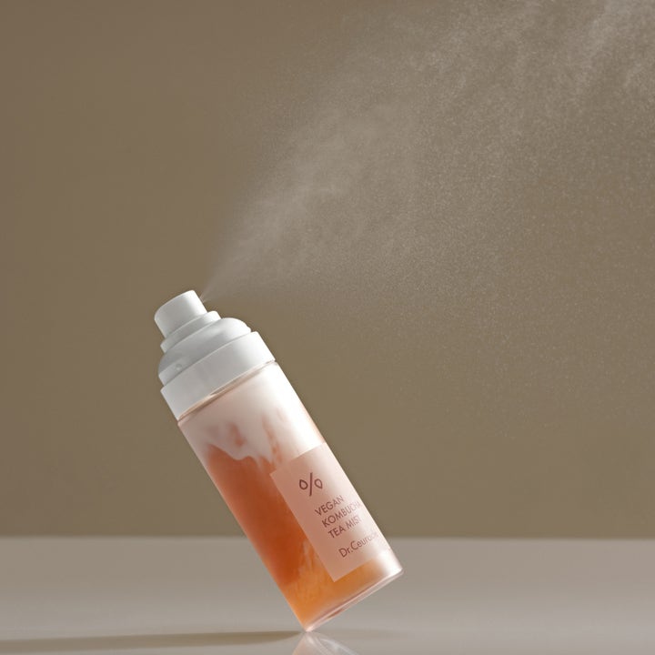 Dr. Ceuracle Vegan Kombucha Tea Mist 80 ml heleyttävä kasvosuihke suihkuttaa hienoa sumua persikkaisesta pullosta.