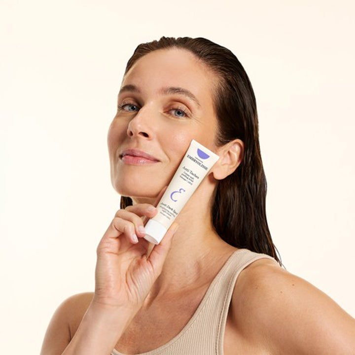 Nainen pitelee Embryolisse Brightening Dark Spot Night Peeling 40 ml nattkräm -tuubia kasvoillaan.