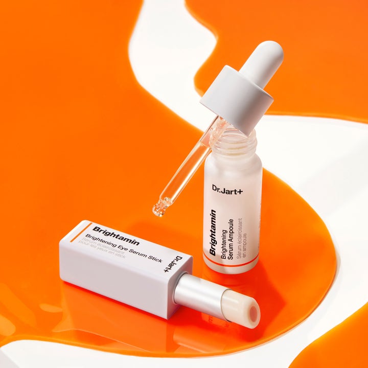 Dr.Jart+ Brightamin Brightening Eye Serum Stick 3,6 g kirkastava silmänympärysvoide ja seerumiampulli oransseilla roiskeilla.