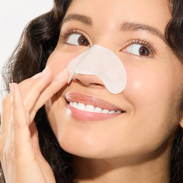 Mario Badescu 2-In-1 Deep Cleansing Pore Strip 6 kpl puhdistava liuska hymyilevän naisen nenällä.