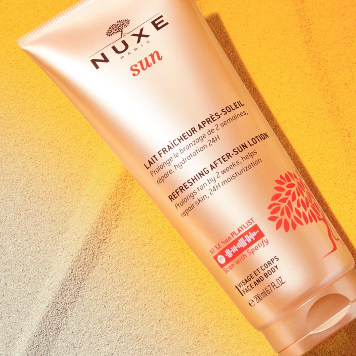 Nuxe Sun Refreshing After Sun Lotion 200 ml pidentää rusketusta ja kosteuttaa ihoa pronssisessa tuubissa hiekalla