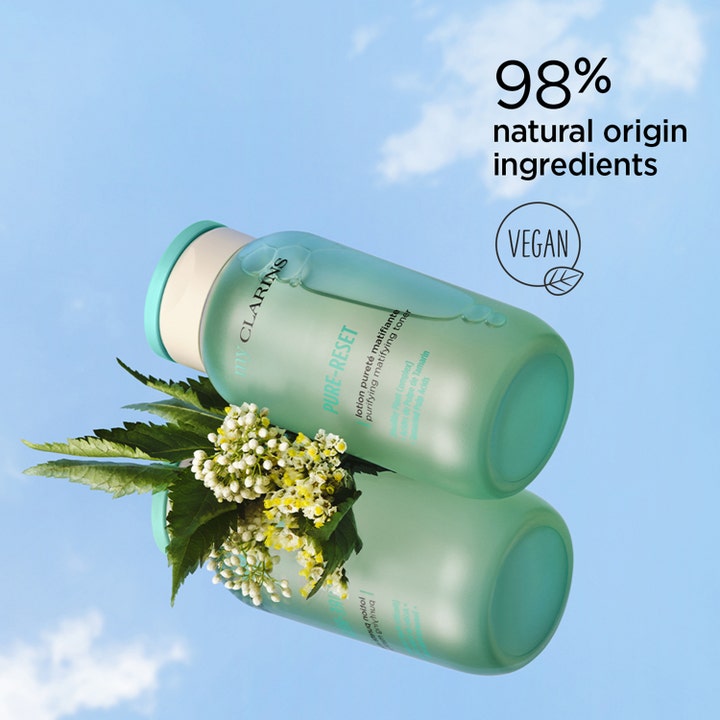 Clarins My Pure-Reset 200 ml puhdistava kasvovesi mattapintaisessa pullossa kukkien kera taivasta vasten.