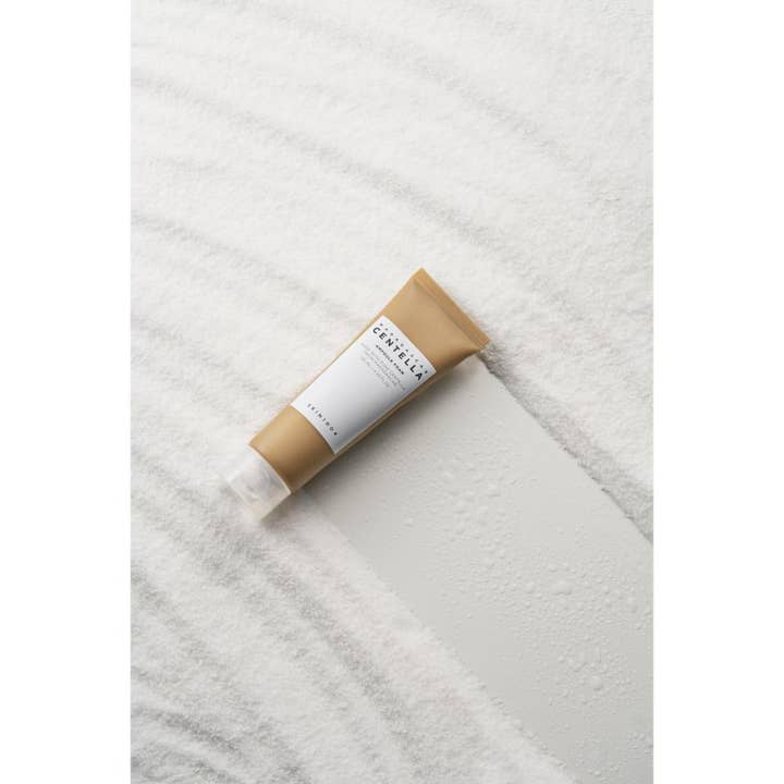 SKIN1004 Madagascar Centella Ampoule Foam 125 ml puhdistusvaahto ruskeassa tuubissa valkoisella hiekalla.
