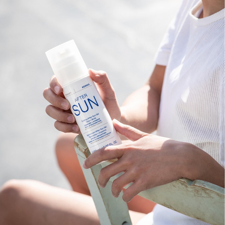 Korres Yoghurt Cooling After-Sun Gel 150 ml viilentävä geeli valkoisessa pumppupullossa henkilön käsissä ulkona