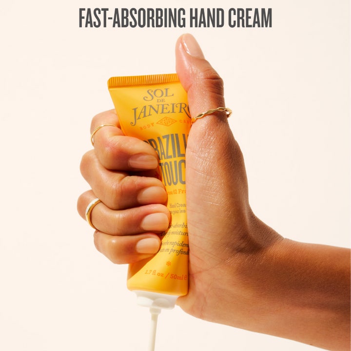 Sol de Janeiro Brazilian Touch 50 ml kosteuttava käsivoide keltaisessa tuubissa useiden käsien pitelemänä.