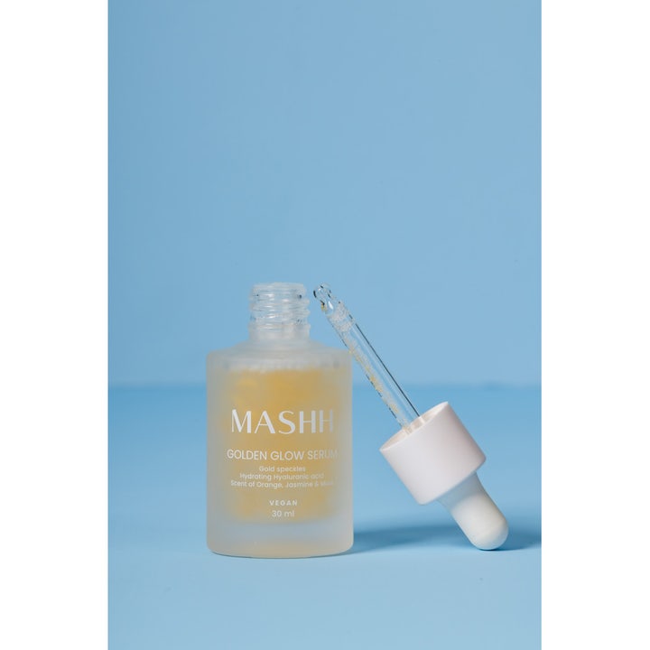 MASHH Golden Glow Serum 30 ml hehkua antava seerumi huurteisessa lasipullossa, jossa on kultahippuja sisältävä pipetti.