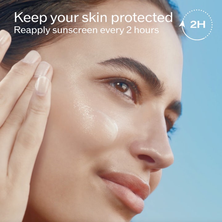 Shiseido Suncare Lotion Sensitive SPF 50 150 ml suojaava aurinkovoide, malli levittää voidetta kasvoilleen.