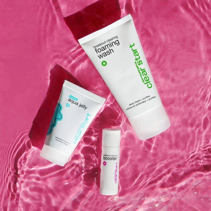 Dermalogica Clear Start Breakout Clearing Kit puhdistava ihonhoitosetti valkoisissa pakkauksissa vaaleanpunaisessa vedessä.