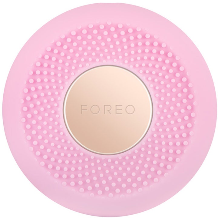 Foreo UFO syväkosteuttava kasvohoitolaite on vaaleanpunainen pyöreä silikonilaite kultaisella logolevyllä.